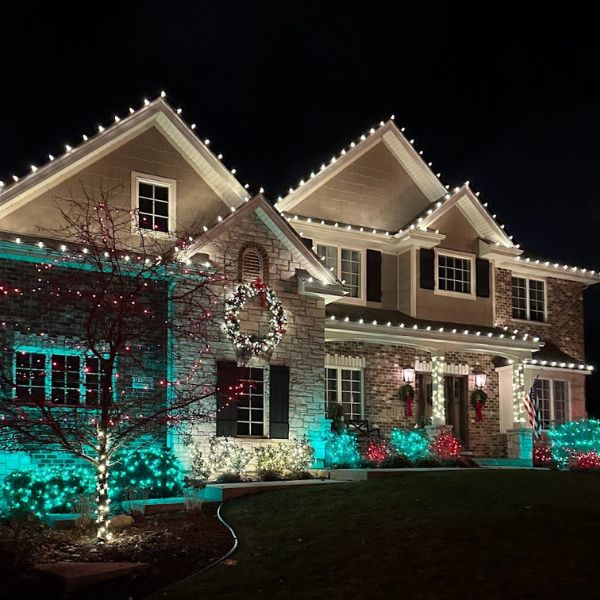 Residential home lit with string lights on roof and windows, cozy festive ambiance